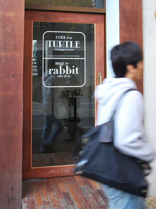 A door for the restaurant "Cork for Turtle; Mug for Rabbit" with the name in white letters on the glass.