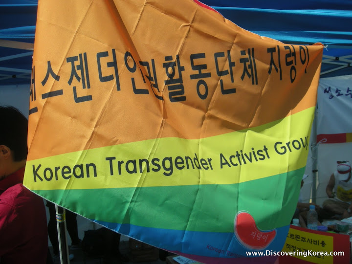 An orange, yellow, green, and blue flag with black Korean lettering and text on it.