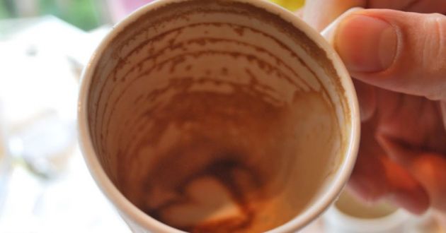 Close up of a white cup emptied of coffee with a small heart shape in the bottom made from frothy milk and chocolate powder.