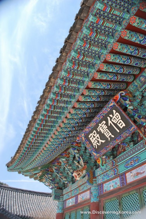 Close up of the ornate wood carvings, intricately painted in predominantly turquoise in the eaves of the roof at Songgwangsa temple.