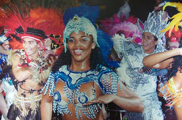 Dancers at Lotte World, a woman dressed in a blue glittery outfit and headdress at the center of the frame, surrounded by men dressed in various fancy dress themes.