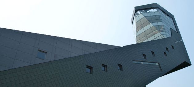 Looking up at the observatory in Seoul's Dream Forest, a long building in dark stone, going upwards to a glass area with panoramic views.