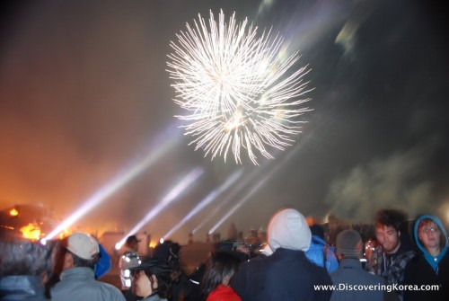 A fireworks display on a soft focus background, with a crowd of people watching, on Jeju island.