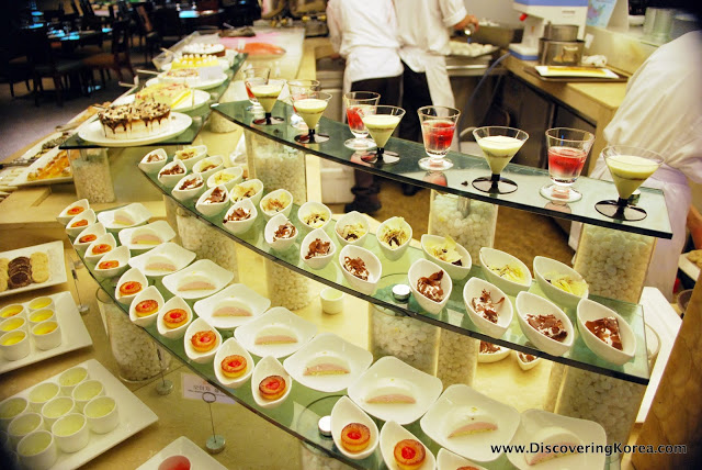 Glass shelves displaying different food in rows of small white bowls.