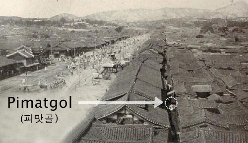 A historical photo of old Seoul, with the river running in the center of the frame and lots of small traditional houses with curved roof. Black text points to a small area between the houses.