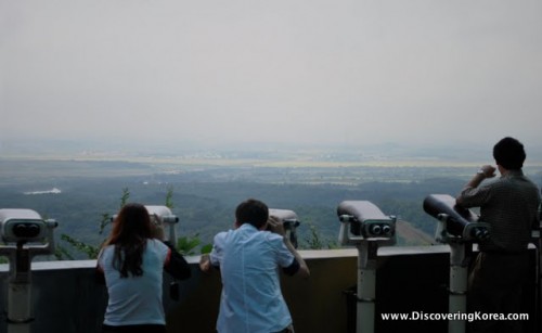 Tourists pictured taking photographs and viewing through binoculars over DMZ.