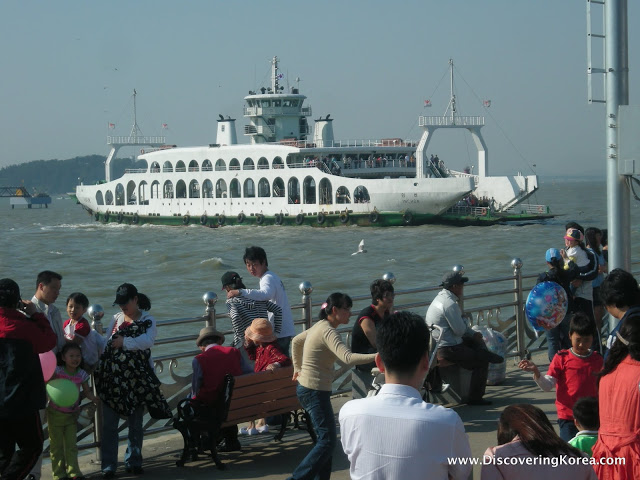 A large passenger ferry in the water, approaching Incheon port. Pedestrians in the foreground.