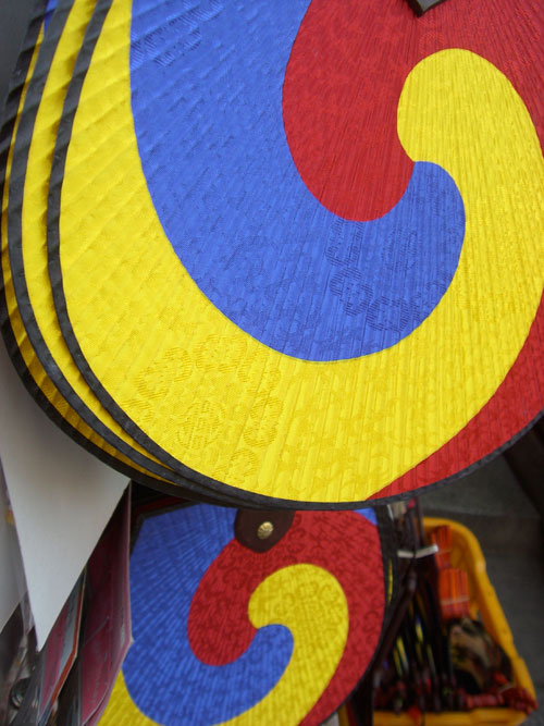 A close up of a Korean fan, in yellow blue and red.