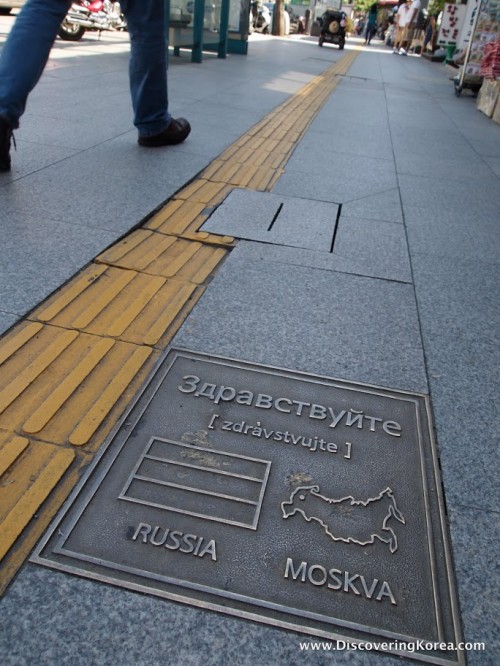 Close up of a pavement inscription in Itaewon, to the right of the frame a man's legs are visible as he walks.