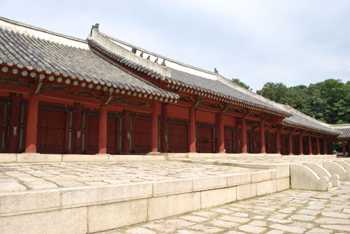 Jongmyo Royal Shrine, a low red building, with dark tiled roof, on light stone.