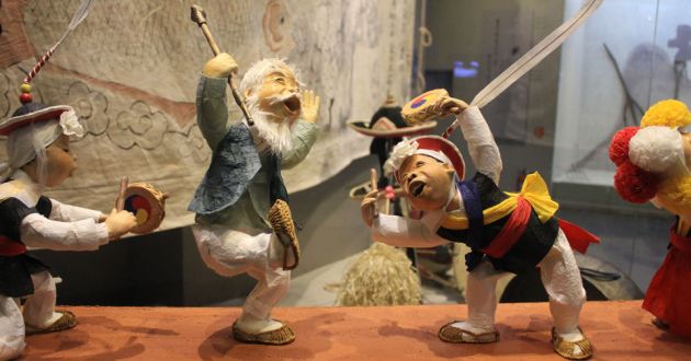 Wooden carvings of men dancing displayed at the National Folk Museum of Seoul.