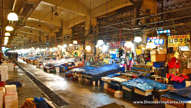Noryangjin fisheries market, a warehouse style building, with stalls selling fresh fish and seafood, brightly lit.
