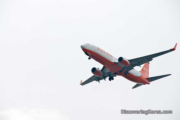 A white and orange airplane flying, on a white background.