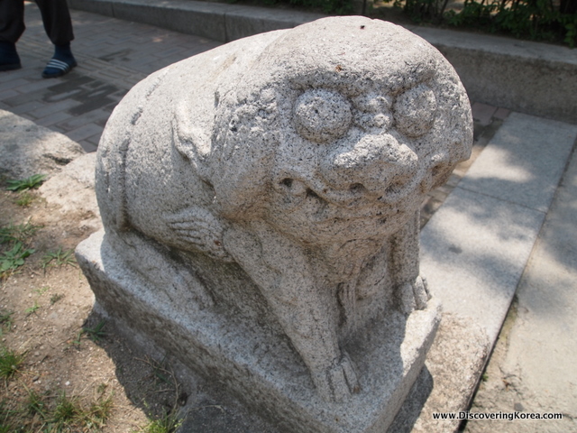 Close up of a carved stone statue of a mythical creature at Dongmyo shrine in Seoul. Pale stone with a soft focus shadowed background.
