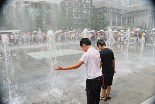 Two children playing in a water fountain, at Gwanghwamun in Seoul.