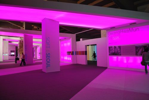 A view into a large expansive room with columns brightly lit in pink light.